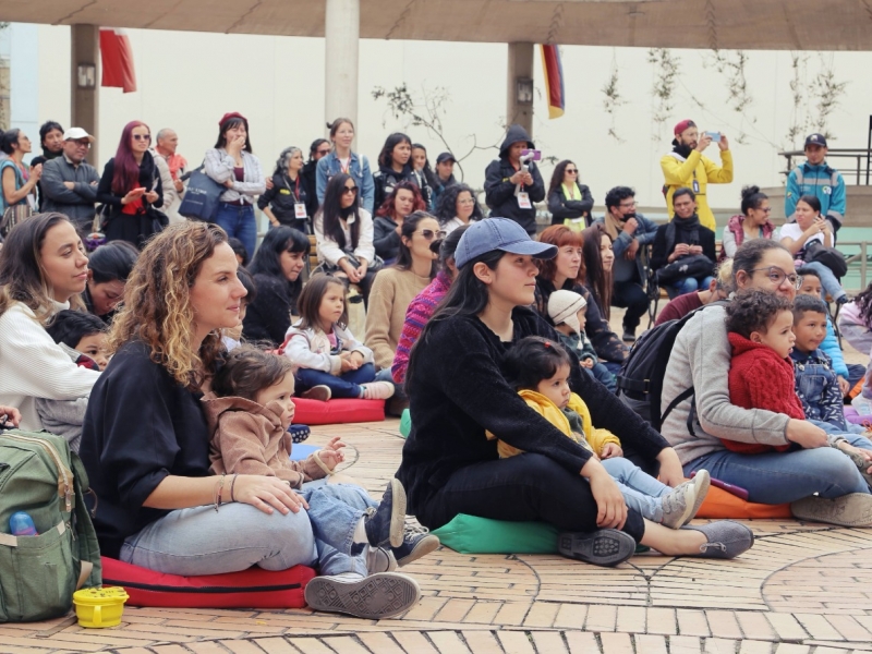 Personas con bebés sentados en el piso viendo presentación