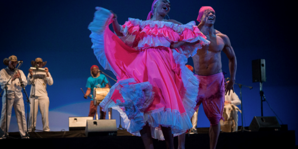 Bailarines danzando en el escenario con trajes coloridos