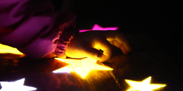 Mano de niño jugando con estrellas iluminadas