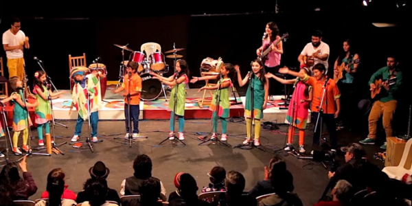 Niños y jovenes en el escenario con instrumentos musicales