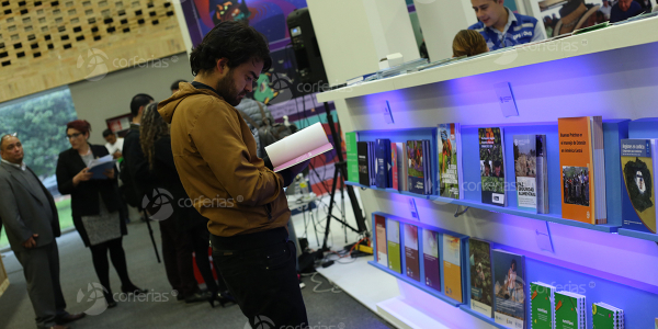 Hombre viendo libro en estand de la Feria del Libro