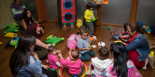 Mujeres y niños participando de una actividad lúdica e instructiva.