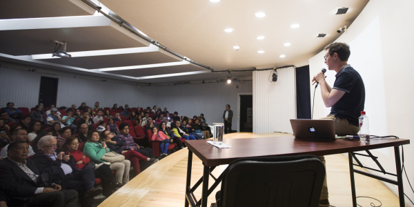 Hombre dando una conferencia en un salón con público