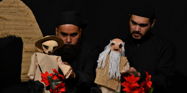 Hombres manejando los títeres en el escenario con flores