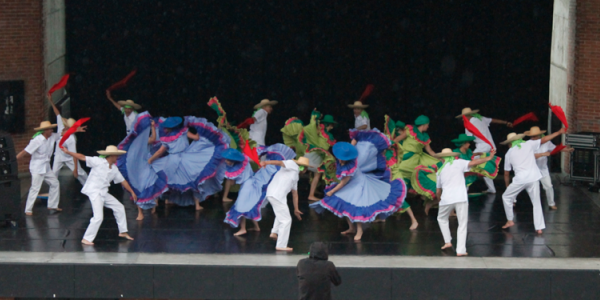 Personas danzando en el escenario con trajes coloridos.