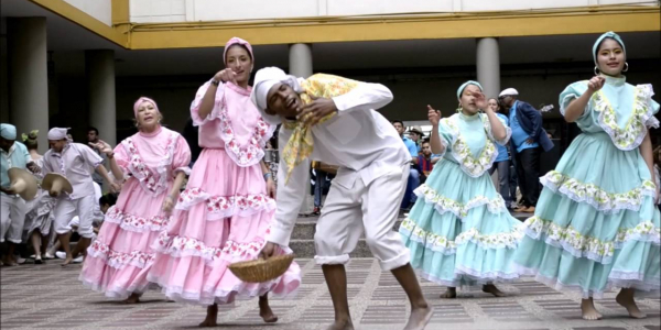 Mujeres bailando y un hombre entre ellas vestido de blanco