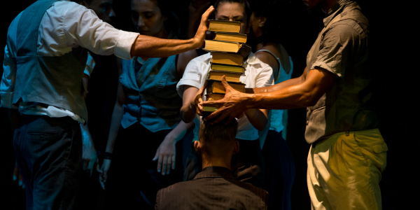 Hombres y mujeres con libros encarrados uno sobre el otro.