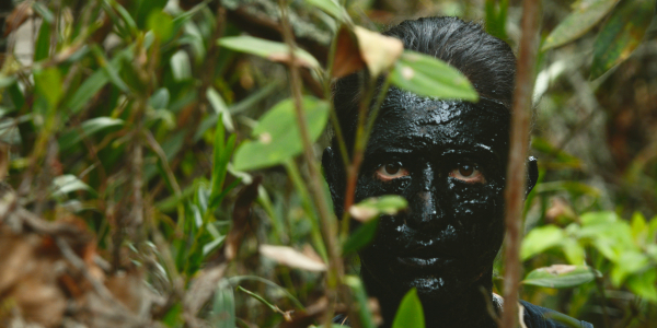 Rostro pintado totalmente de negro en medio de la vegetación