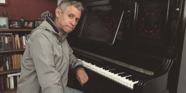 Hombre posando frente a la cámara en estudio con piano