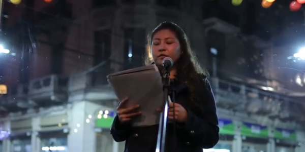 Joven mujer leyendo un texto en una calle durante la noche.