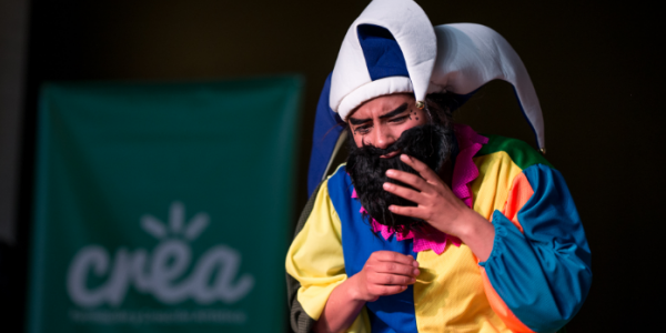 Hombre actuando vestido con traje de colores, gorro y barba negra