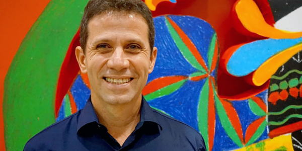 Roger Mello sonriendo con fondo de colores