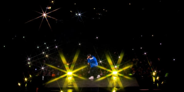 Hombre en una tarima cantando en un concierto realizado en la noche.