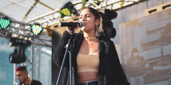 Fotografía de una mujer en escena cantando frente a un micrófono