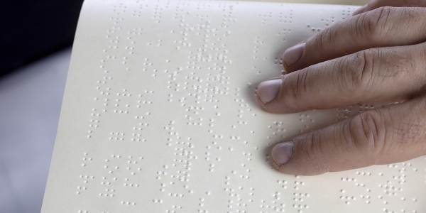 Mano sobre texto en braille. 