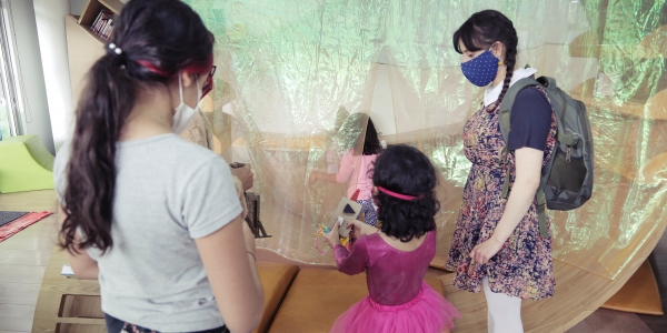 Artistas del Programa Nidos compartiendo con una niña en primera infancia durante experiencia artística.