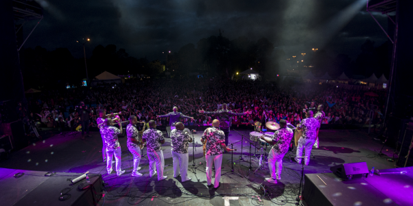 Personas en escena con instrumentos y público en la noche