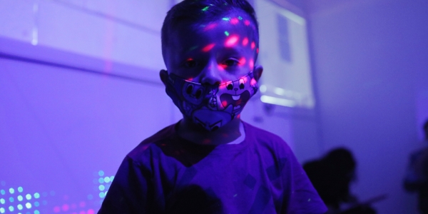 Niño en primera infancia con luces de colores en su rosdtro