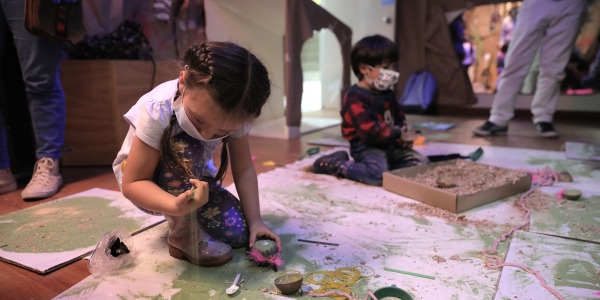 Niña y niño jugando con materias y materiales en ambientación efímera