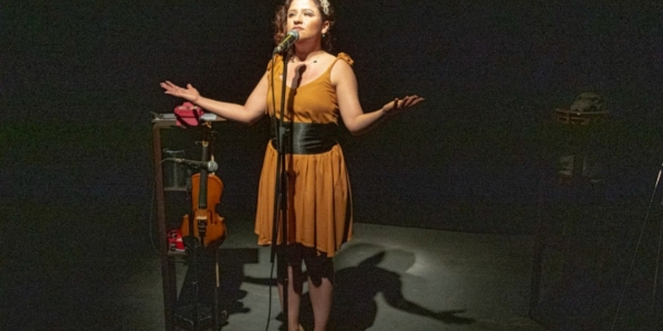 Fotografía de una mujer en escena cantando frente a un micrófono