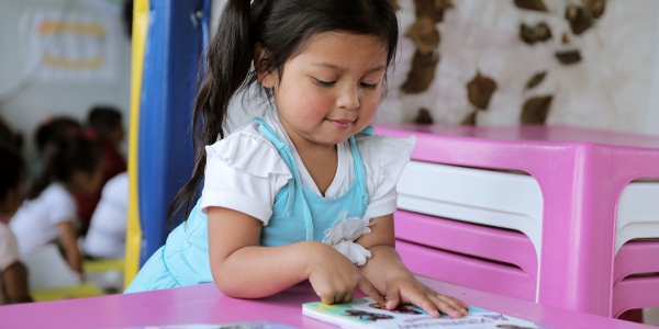 Niña en primera infancia mirando un libro.