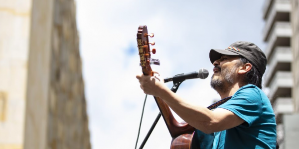 Señor con camiseta azul cantando en una tarima 