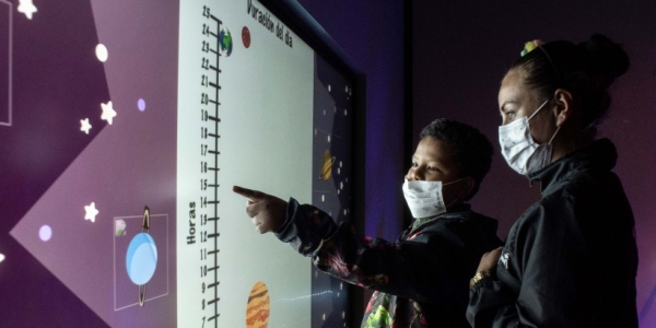 Dos personas con una pantalla táctil en el Planetario. 