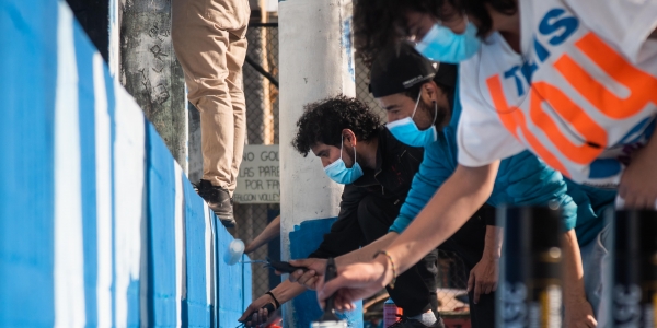 Grupo de personas pintan una zona bajo puente con rodillos