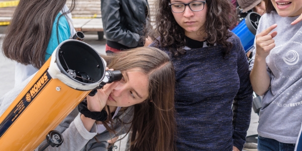 Niñas observando por telescopio. 