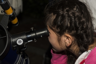 Niña viendo la  luna a través de un telescopio 