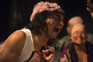 Hombre de cabello largo llorando, con otros actores al fondo.