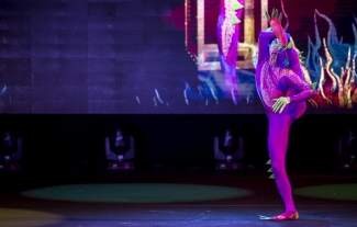 Actor con traje rosa con una pierna detrás de la oreja