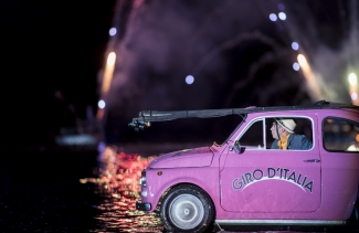 Carro fucsia con conductor sobre el lago