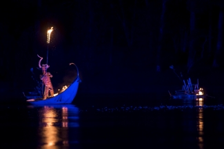 Hombre sobre góndola azul en el lago.