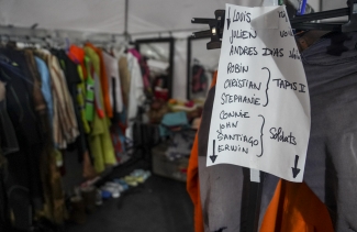 Cuarto con trajes de actores y lista de nombres.