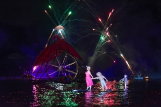 Rueda gigante y mujer con niño - marioneta sobre el lago iluminado.