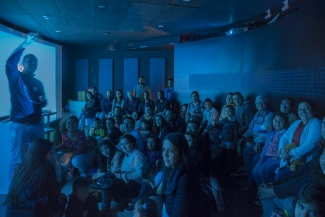 Grupo de personas recibiendo información de un funcionario del Planetario 