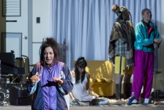 Mujer  actuando en el escenario con personas al fondo