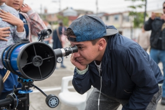 Joven observando por telescopio.