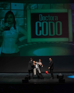 Dos actores llevan en brazos a otro actor de la obra.